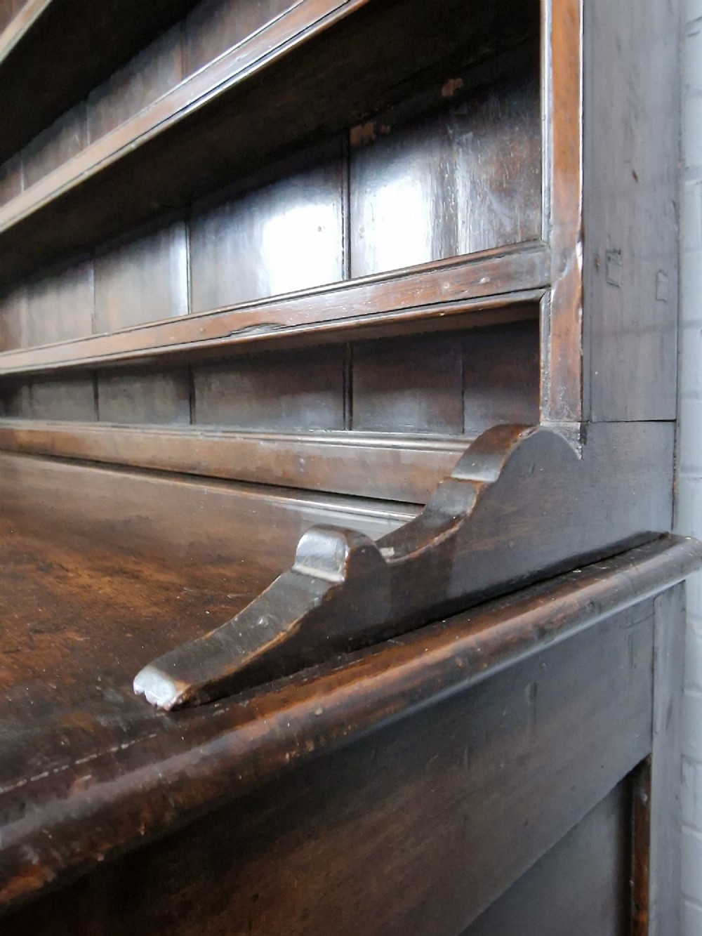 An antique dark oak dresser featuring a three-shelf open plate rack mounted above a base with multiple drawers and lower panelled cupboard doors. View III