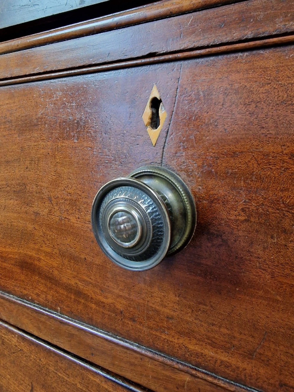 An early nineteenth-century George IV flame mahogany linen press featuring a double-door upper cupboard over a chest of drawers with bracket feet. View VIII
