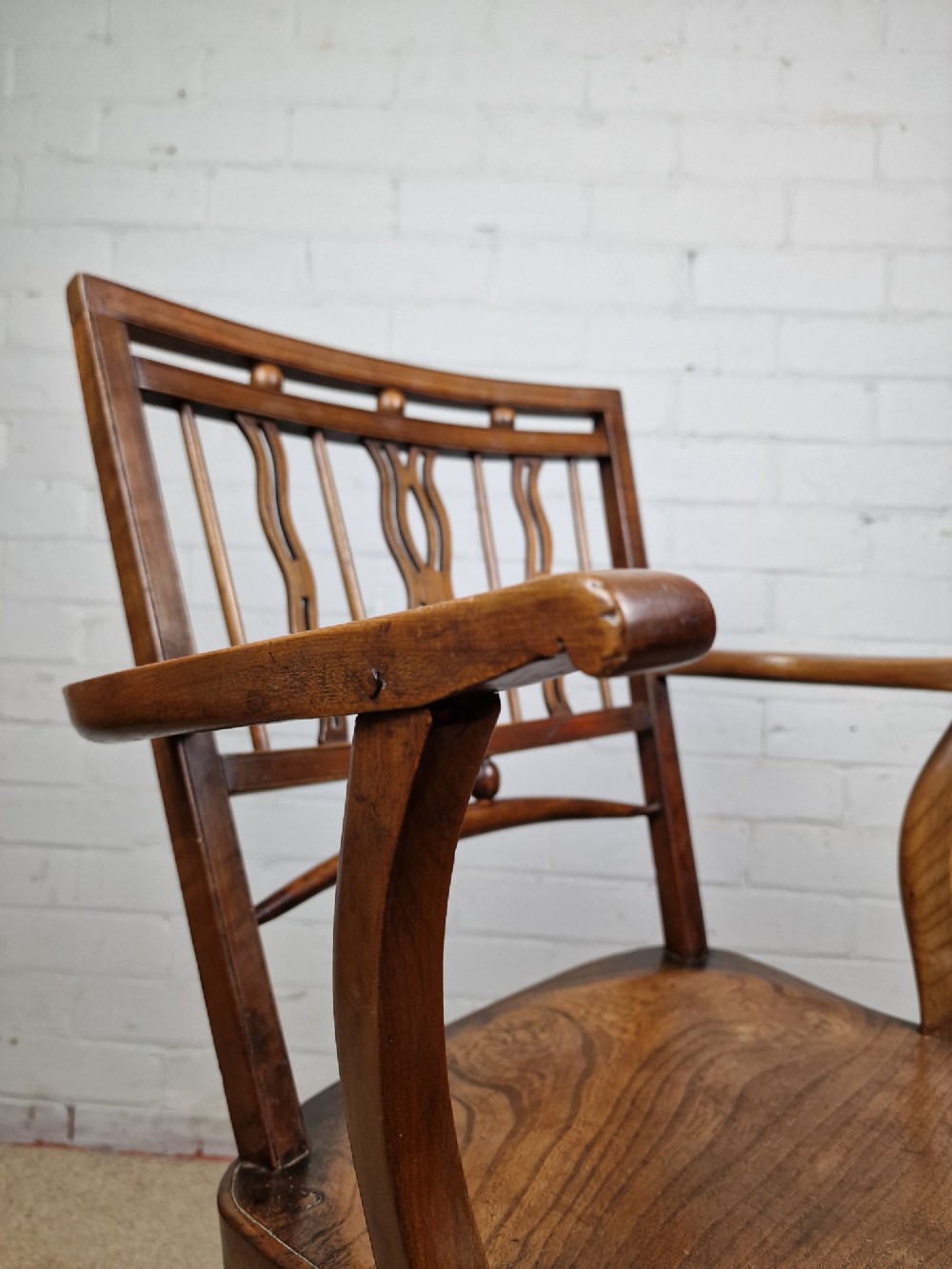 A mid-19th-century wooden Mendlesham armchair featuring a squared backrest with turned wooden spheres, pierced splats, curved arms, and a shaped seat on turned legs. View V