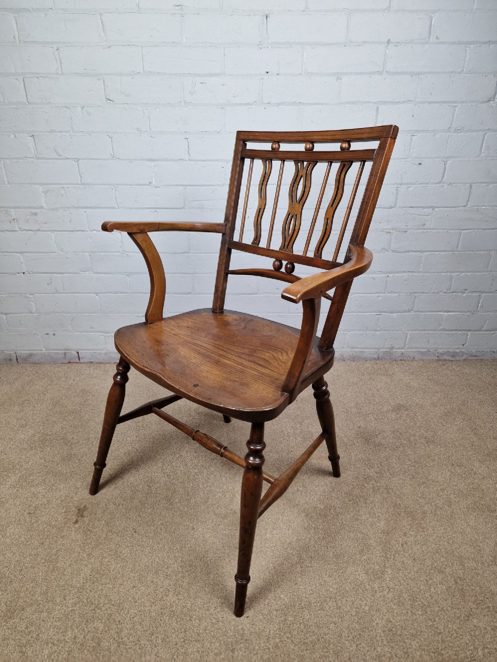 A mid-19th-century wooden Mendlesham armchair featuring a squared backrest with turned wooden spheres, pierced splats, curved arms, and a shaped seat on turned legs. View XI