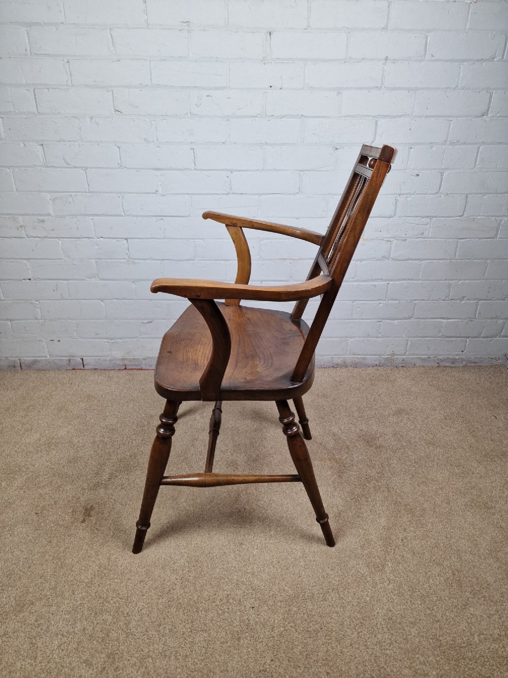 A mid-19th-century wooden Mendlesham armchair featuring a squared backrest with turned wooden spheres, pierced splats, curved arms, and a shaped seat on turned legs. View XII
