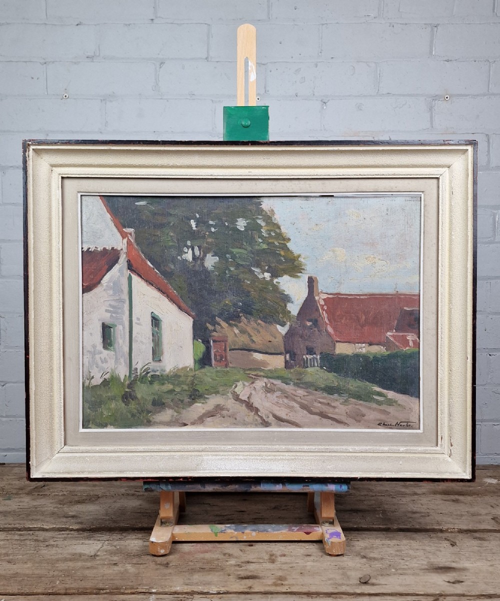 An oil painting on board depicting a Belgian farmyard scene with whitewashed cottages and trees, housed in a wide off-white molded frame.