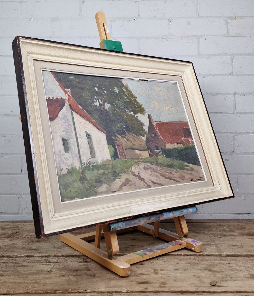 An oil painting on board depicting a Belgian farmyard scene with whitewashed cottages and trees, housed in a wide off-white molded frame. View VI
