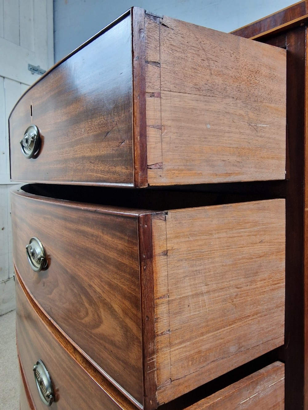 A George III mahogany bowfront chest of drawers featuring two short over three long graduating drawers with brass handles and splay bracket feet. View VI