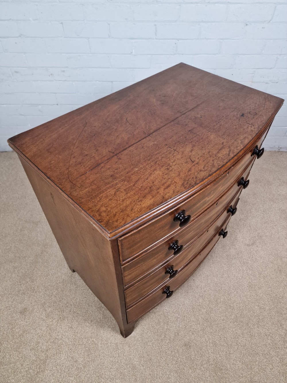 A George III mahogany bow front chest of drawers featuring four graduated drawers with dark turned wooden handles and splayed bracket feet. View VI