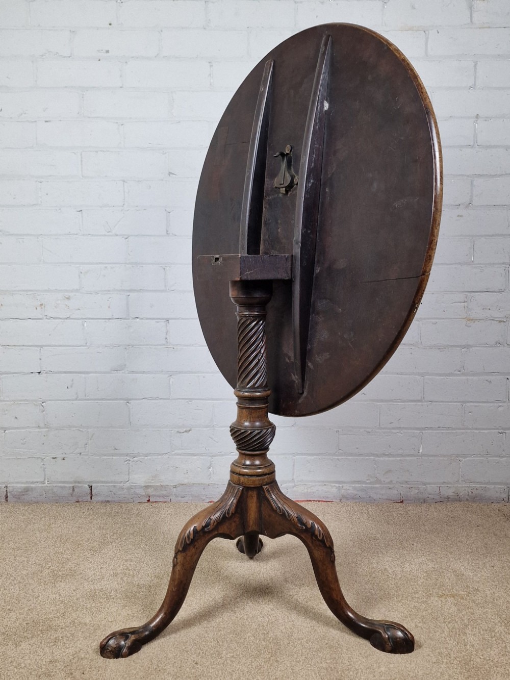 An 18th-century George II walnut tilt-top table featuring a circular top resting on a spiral-twisted column, carved cabriole legs, and claw and ball feet. View V