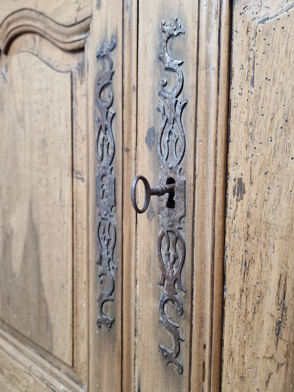 An antique French provincial two-door wooden side cabinet featuring carved panel doors, iron escutcheons, and short cabriole legs. View III