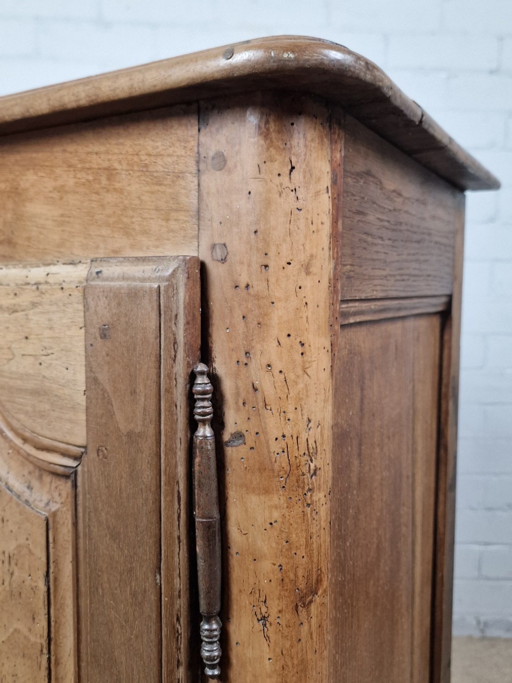 An antique French provincial two-door wooden side cabinet featuring carved panel doors, iron escutcheons, and short cabriole legs. View IV