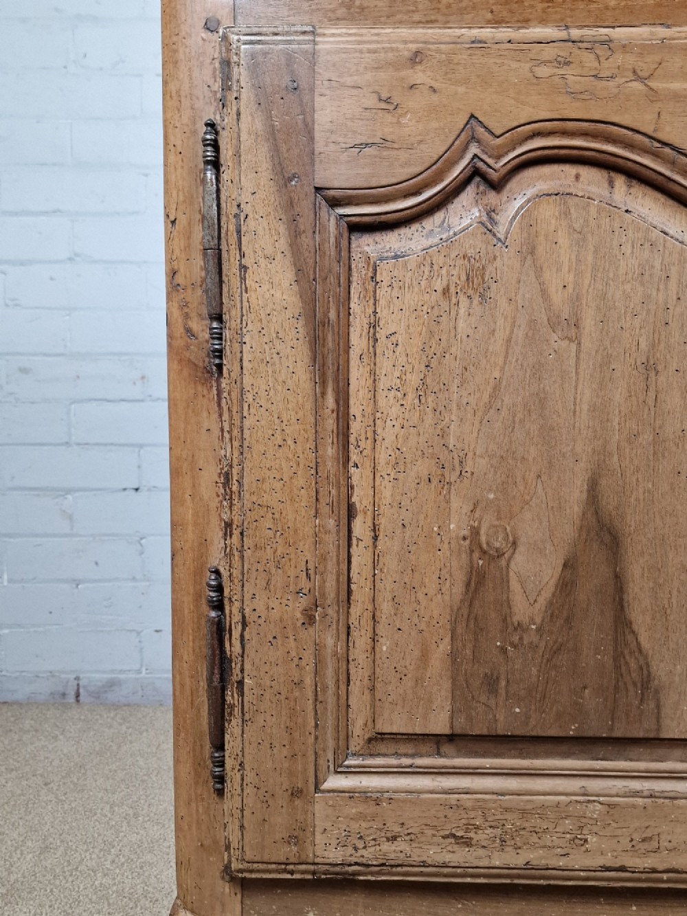 An antique French provincial two-door wooden side cabinet featuring carved panel doors, iron escutcheons, and short cabriole legs. View VI