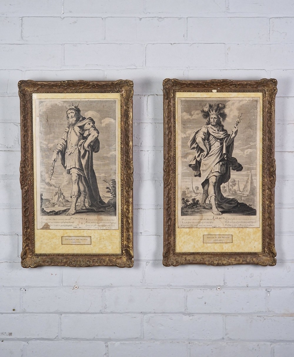 A pair of framed monochrome antique engravings depicting classical male figures set within carved ornate giltwood frames.