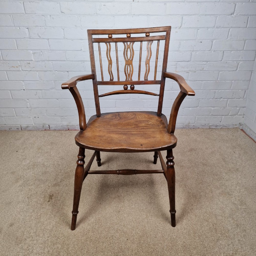 A mid-19th-century wooden Mendlesham armchair featuring a squared backrest with turned wooden spheres, pierced splats, curved arms, and a shaped seat on turned legs. View II