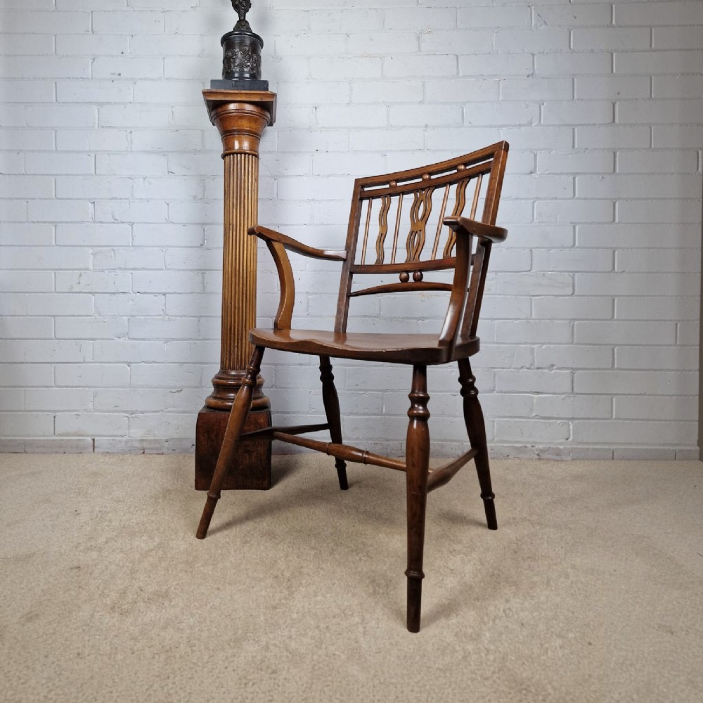 A mid-19th-century wooden Mendlesham armchair featuring a squared backrest with turned wooden spheres, pierced splats, curved arms, and a shaped seat on turned legs. View XI