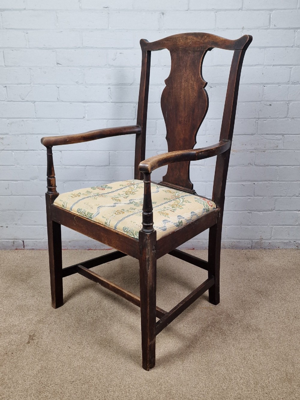 A late eighteenth-century dark oak armchair featuring a vase-shaped splat back, turned arm supports, and a patterned floral fabric drop-in seat. View II