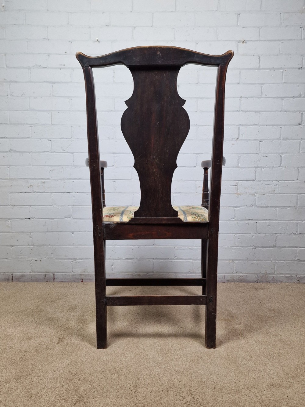 A late eighteenth-century dark oak armchair featuring a vase-shaped splat back, turned arm supports, and a patterned floral fabric drop-in seat. View V