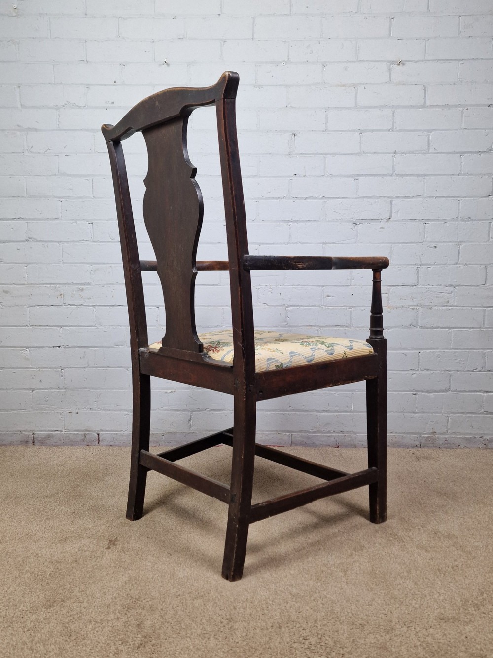 A late eighteenth-century dark oak armchair featuring a vase-shaped splat back, turned arm supports, and a patterned floral fabric drop-in seat. View VI