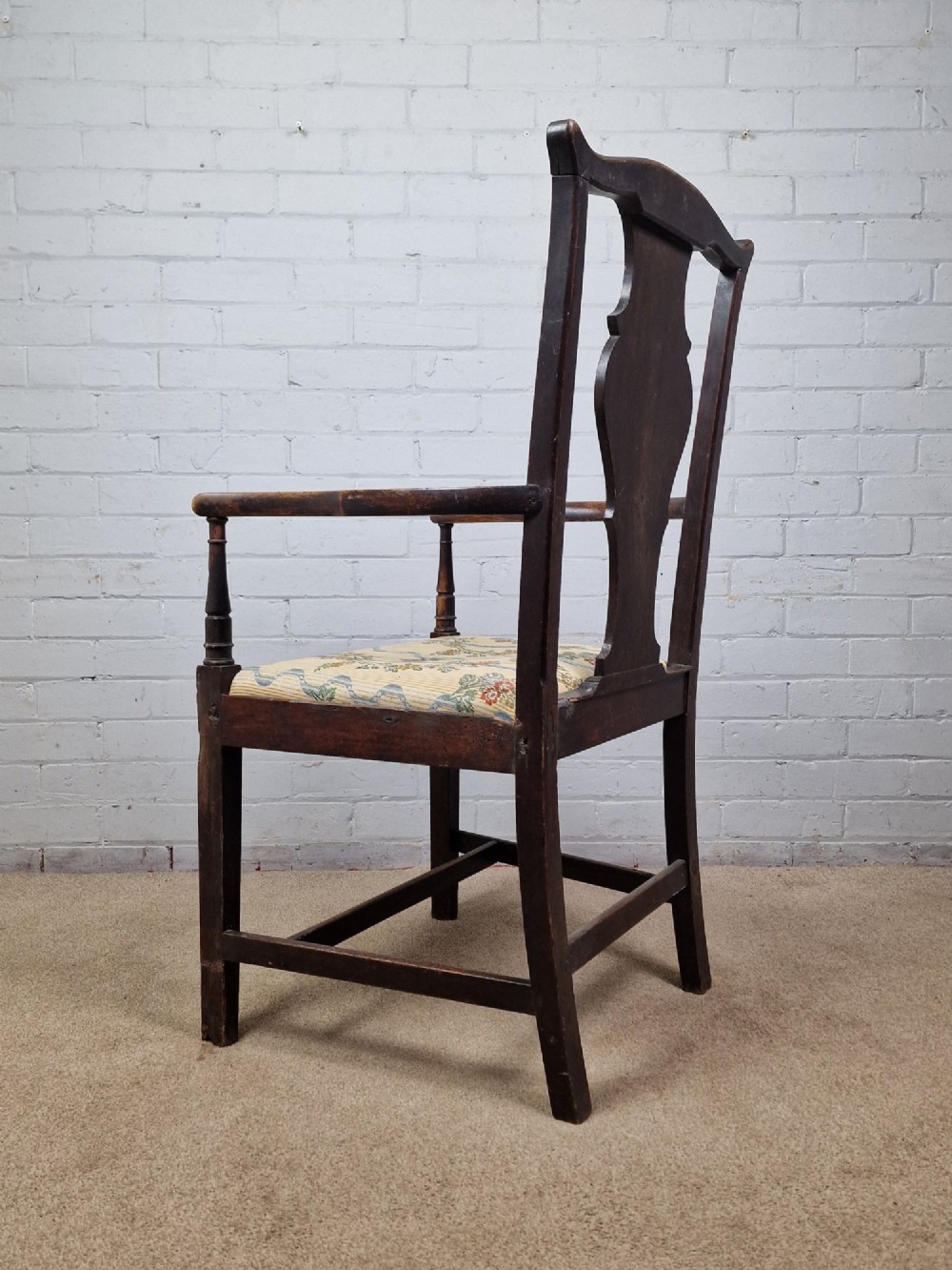 A late eighteenth-century dark oak armchair featuring a vase-shaped splat back, turned arm supports, and a patterned floral fabric drop-in seat. View VII