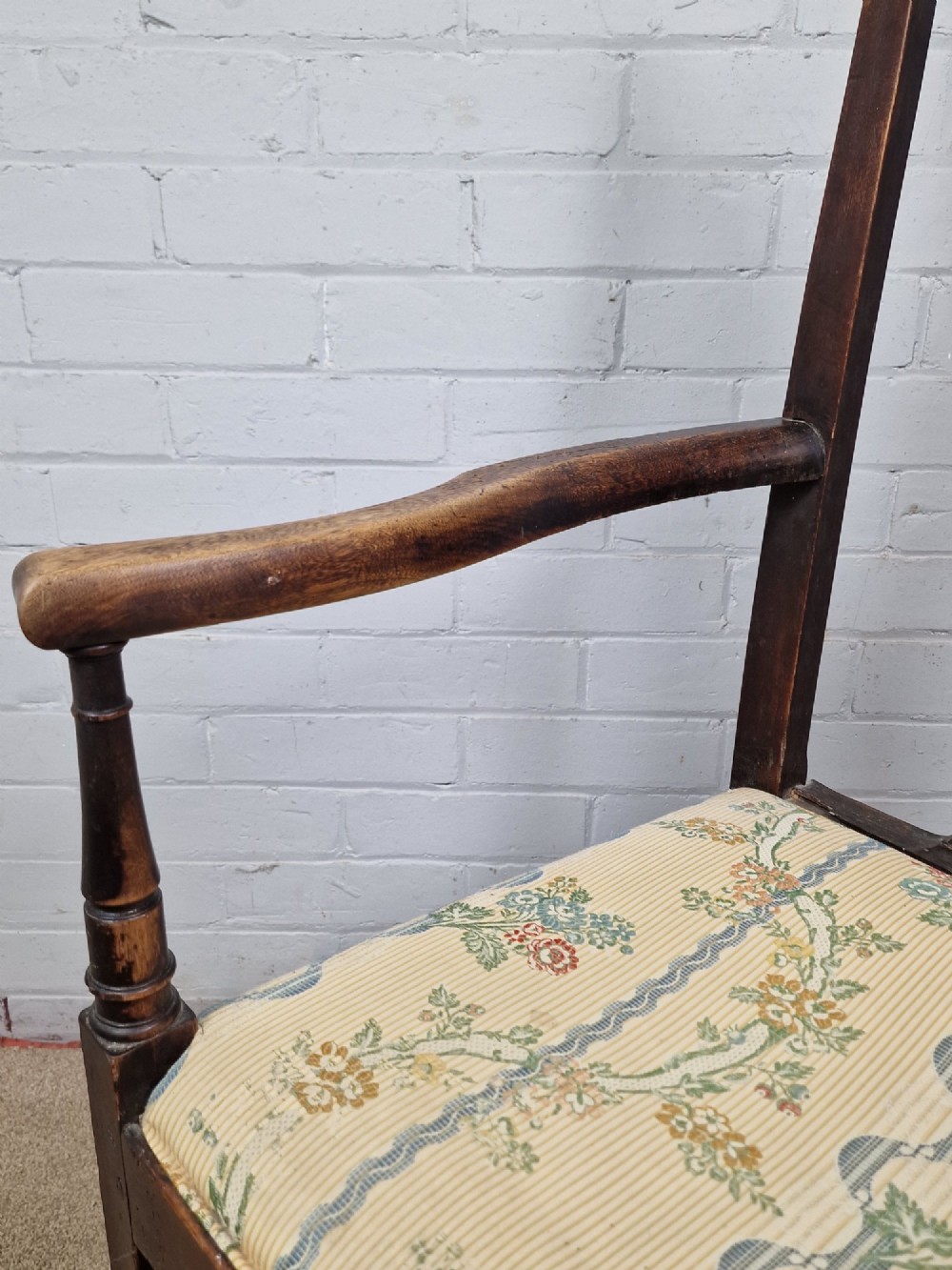 A late eighteenth-century dark oak armchair featuring a vase-shaped splat back, turned arm supports, and a patterned floral fabric drop-in seat. View X