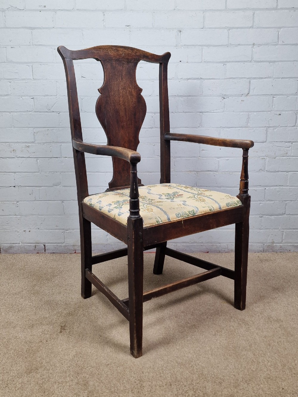 A late eighteenth-century dark oak armchair featuring a vase-shaped splat back, turned arm supports, and a patterned floral fabric drop-in seat. View XII