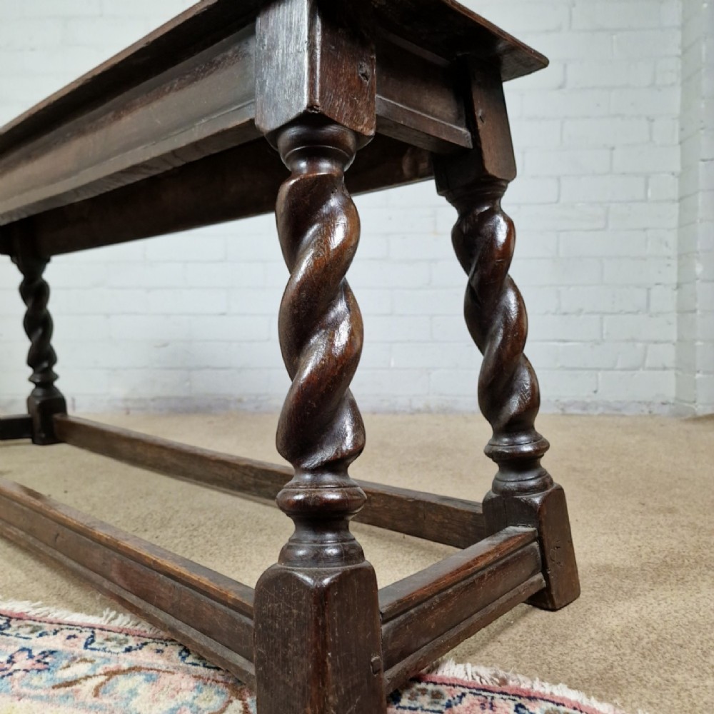An 18th-century dark oak long stool featuring four barley twist legs connected by low stretchers beneath a solid rectangular top. View III