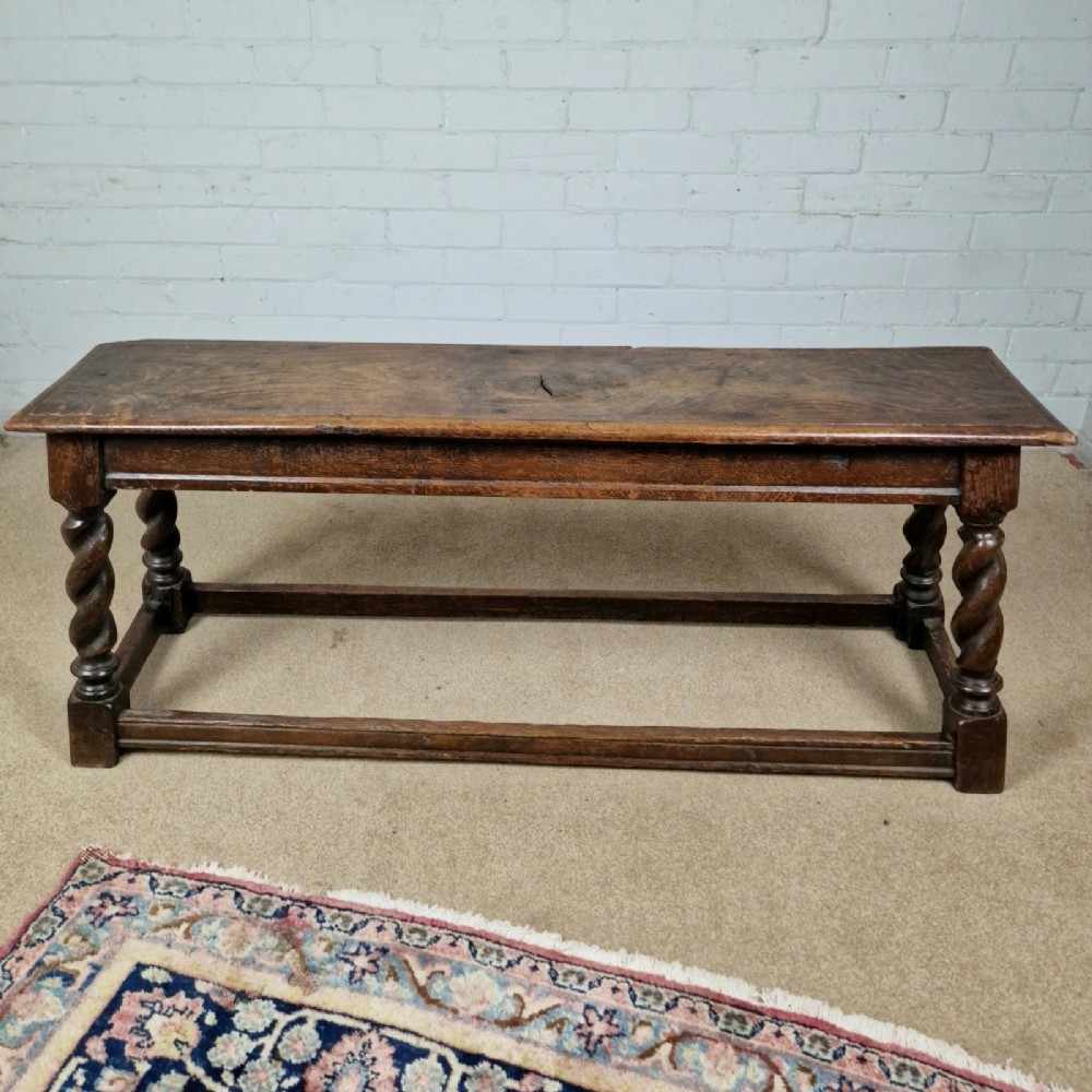 An 18th-century dark oak long stool featuring four barley twist legs connected by low stretchers beneath a solid rectangular top. View VII