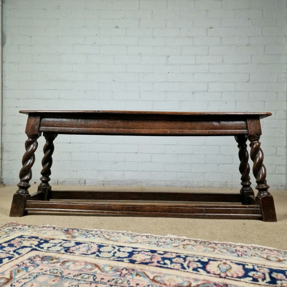 An 18th-century dark oak long stool featuring four barley twist legs connected by low stretchers beneath a solid rectangular top. View VIII