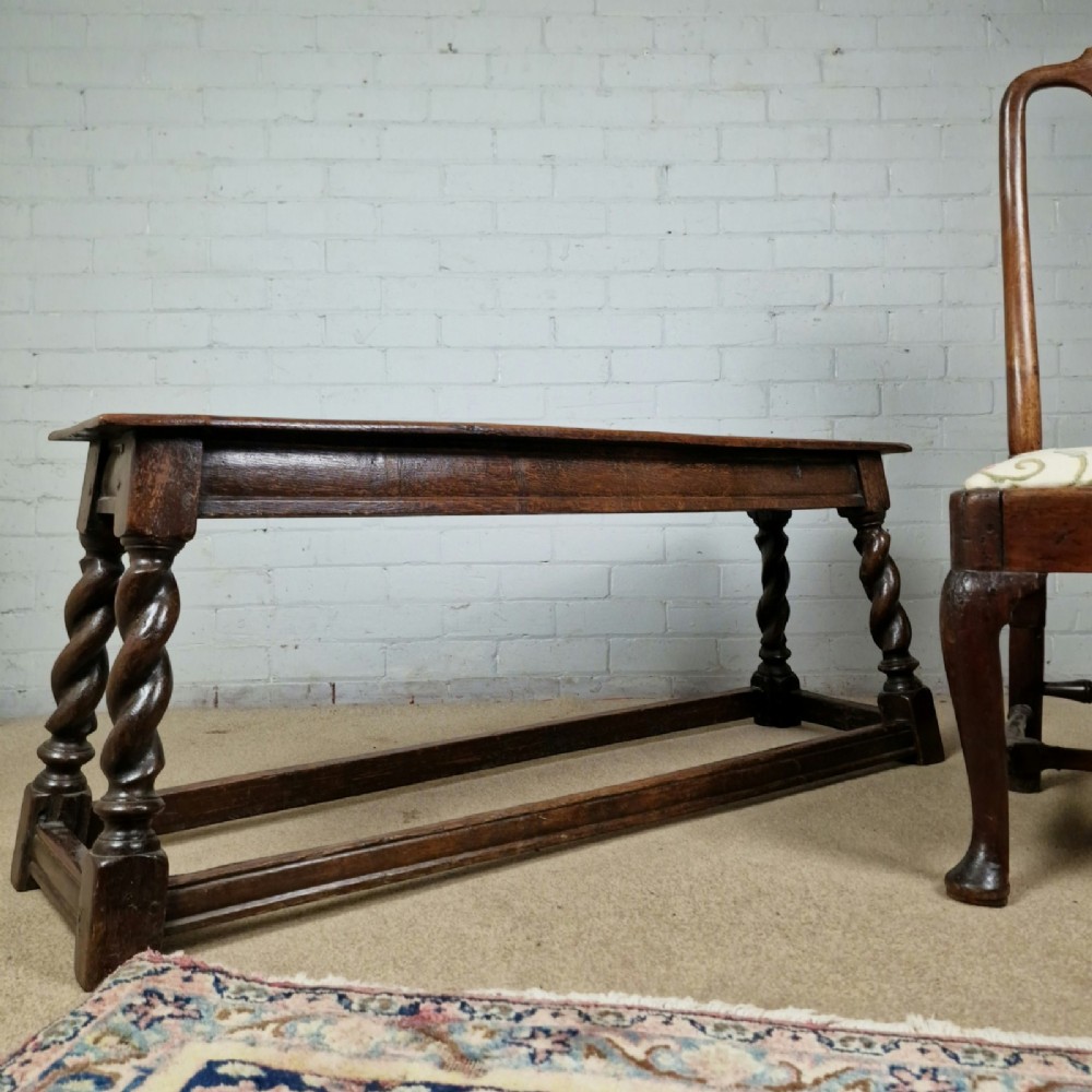 An 18th-century dark oak long stool featuring four barley twist legs connected by low stretchers beneath a solid rectangular top. View IX