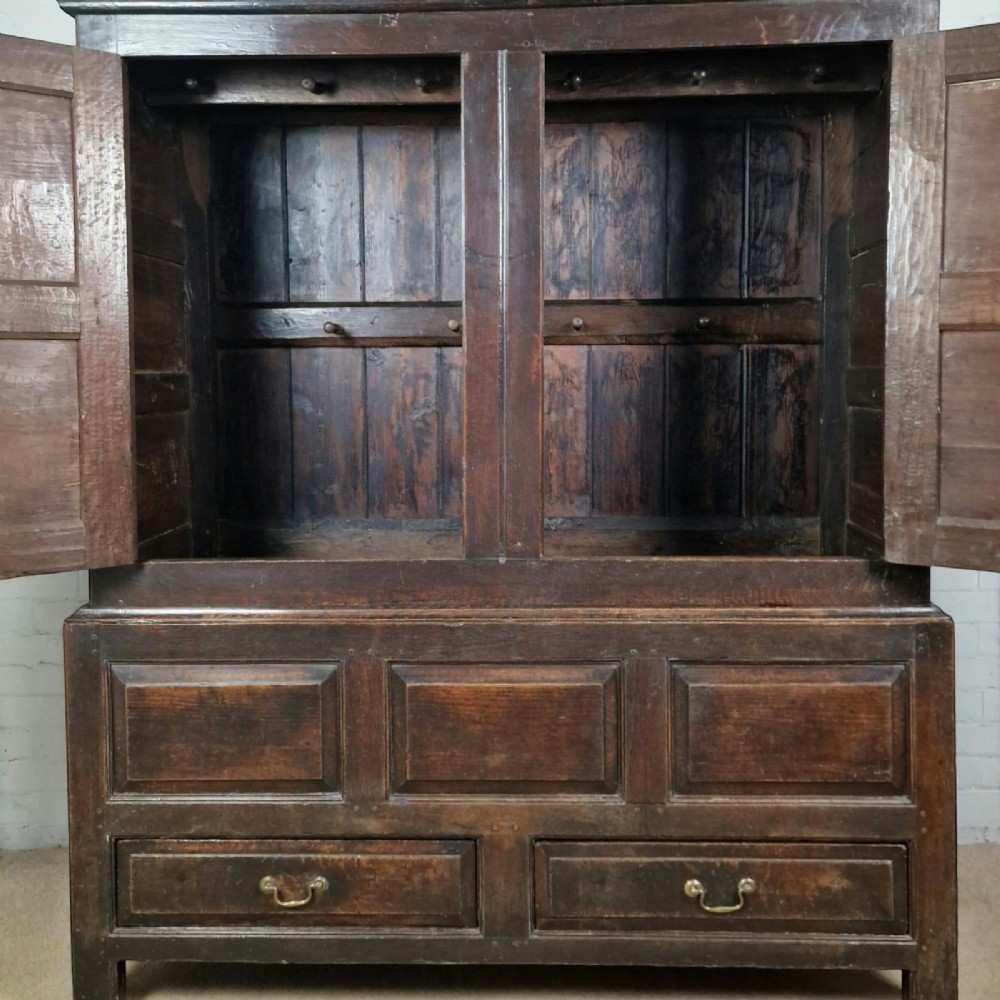 A mid-18th-century dark oak Georgian livery cupboard featuring raised panel doors, brass fittings, and lower drawers. View III
