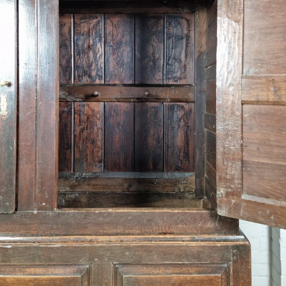 A mid-18th-century dark oak Georgian livery cupboard featuring raised panel doors, brass fittings, and lower drawers. View IV