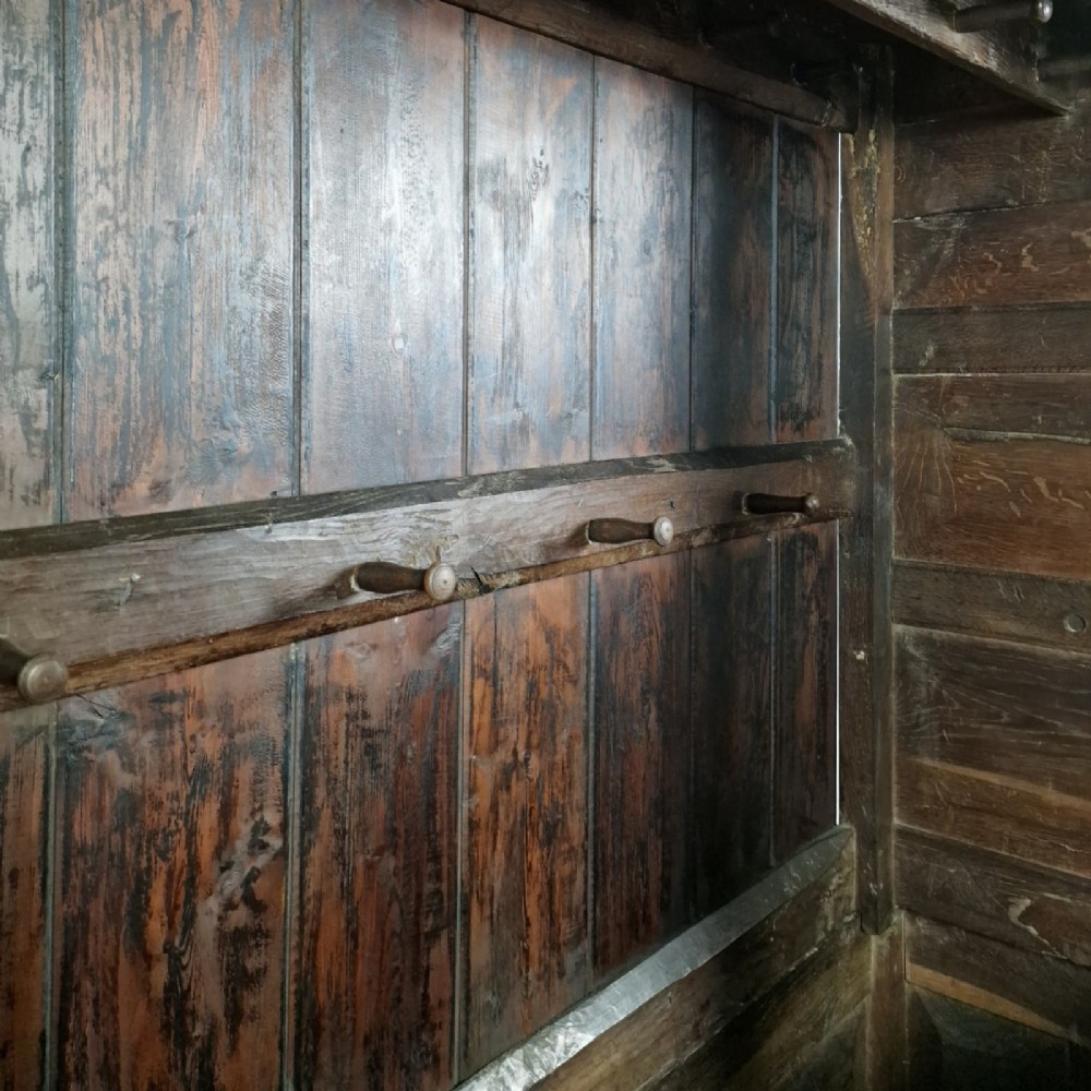 A mid-18th-century dark oak Georgian livery cupboard featuring raised panel doors, brass fittings, and lower drawers. View V