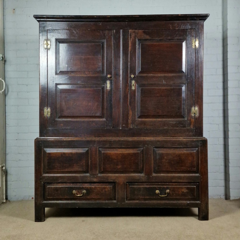 A mid-18th-century dark oak Georgian livery cupboard featuring raised panel doors, brass fittings, and lower drawers. View VII