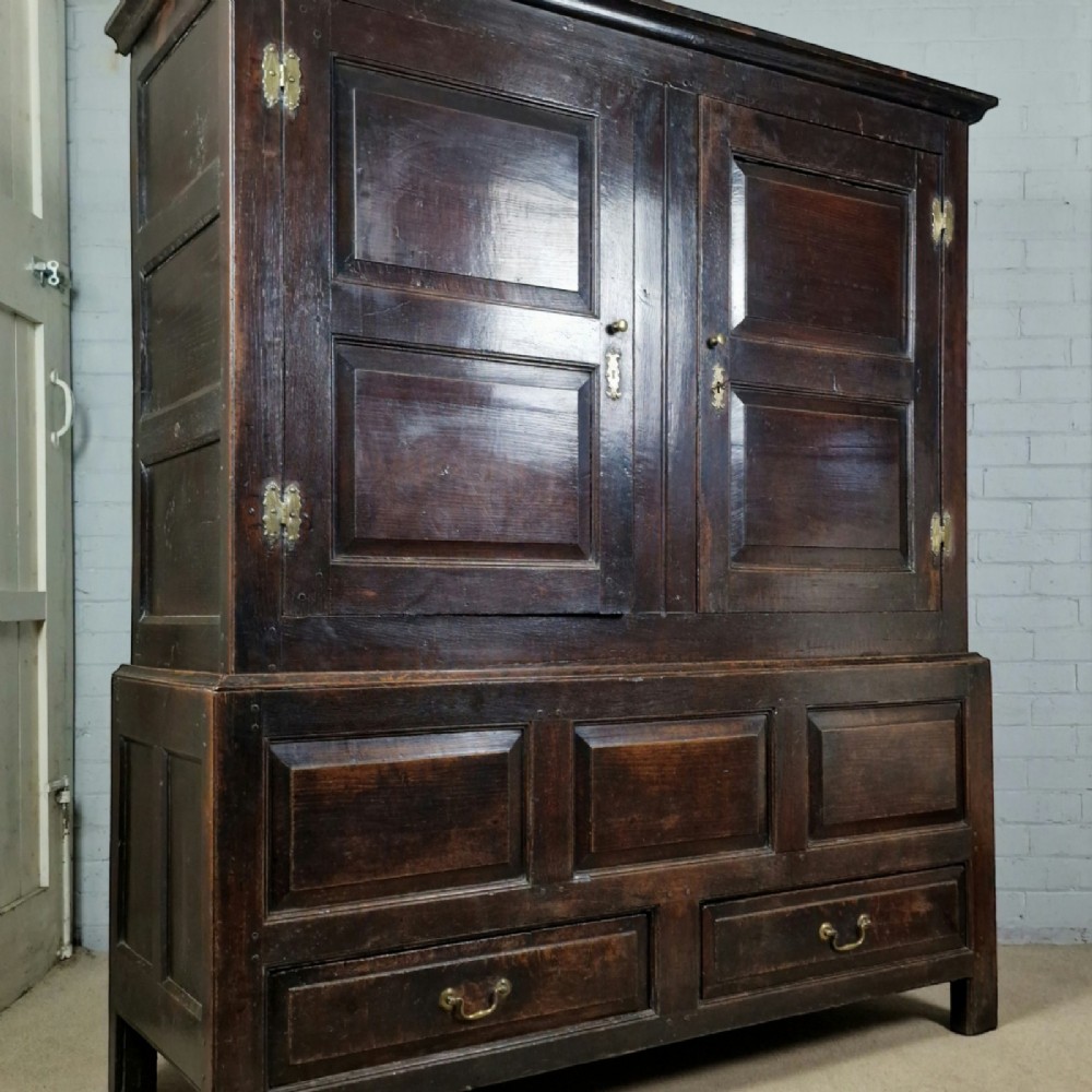 A mid-18th-century dark oak Georgian livery cupboard featuring raised panel doors, brass fittings, and lower drawers. View VIII