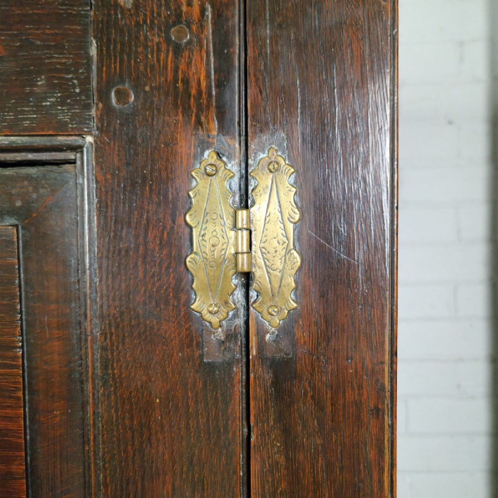 A mid-18th-century dark oak Georgian livery cupboard featuring raised panel doors, brass fittings, and lower drawers. View X