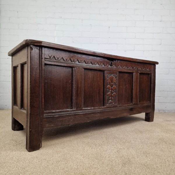 A seventeenth-century dark oak joined coffer featuring a carved central floral panel, a geometric top frieze, and a panelled front facade. View III