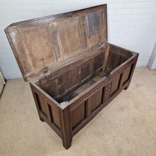 A seventeenth-century dark oak joined coffer featuring a carved central floral panel, a geometric top frieze, and a panelled front facade. View IV