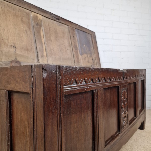 A seventeenth-century dark oak joined coffer featuring a carved central floral panel, a geometric top frieze, and a panelled front facade. View VIII