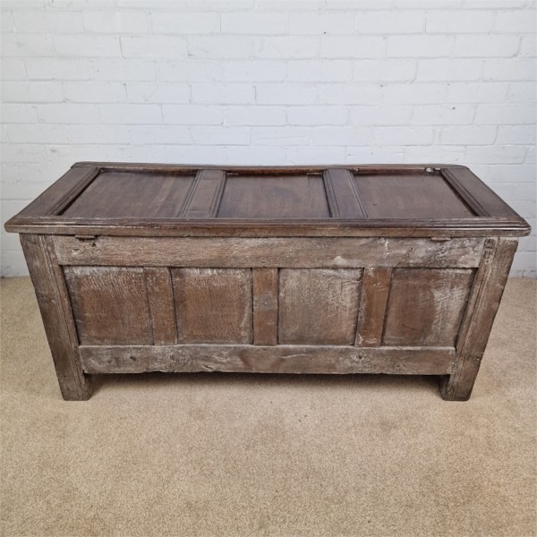 A seventeenth-century dark oak joined coffer featuring a carved central floral panel, a geometric top frieze, and a panelled front facade. View IX