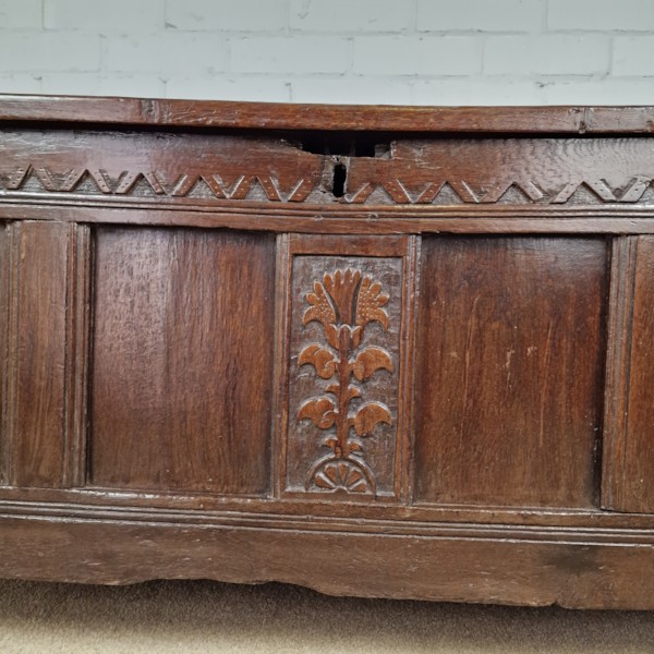 A seventeenth-century dark oak joined coffer featuring a carved central floral panel, a geometric top frieze, and a panelled front facade. View XII