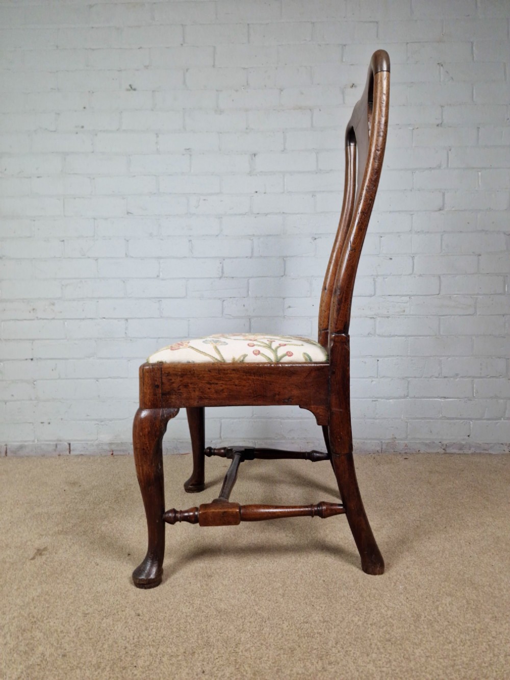 An early 18th century Queen Anne wooden dining chair featuring cabriole front legs, a vasiform back splat, and a patterned drop-in seat cushion. View II