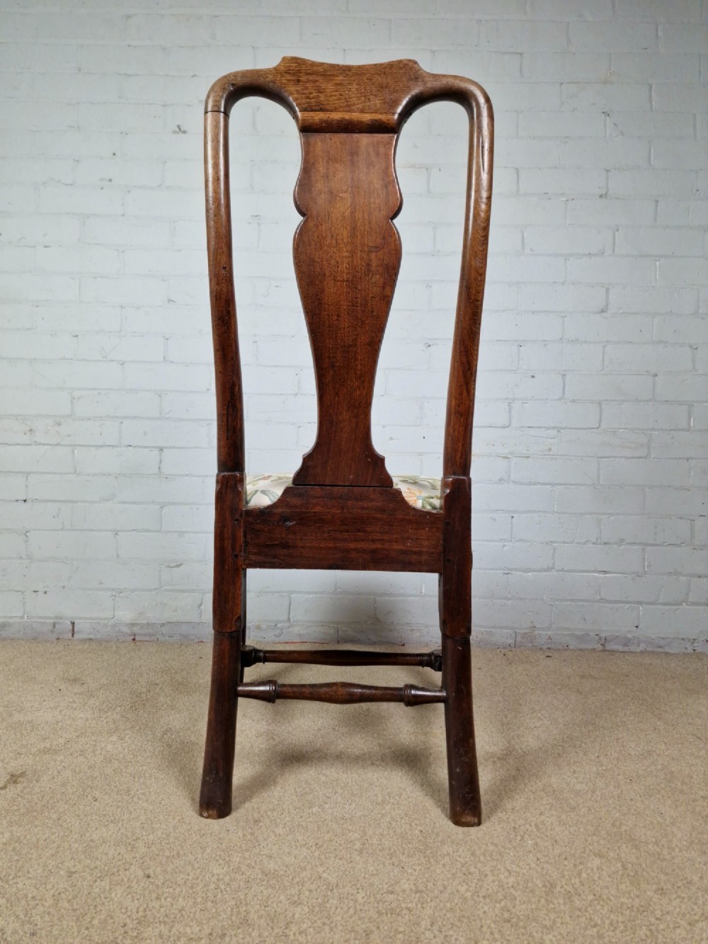 An early 18th century Queen Anne wooden dining chair featuring cabriole front legs, a vasiform back splat, and a patterned drop-in seat cushion. View III