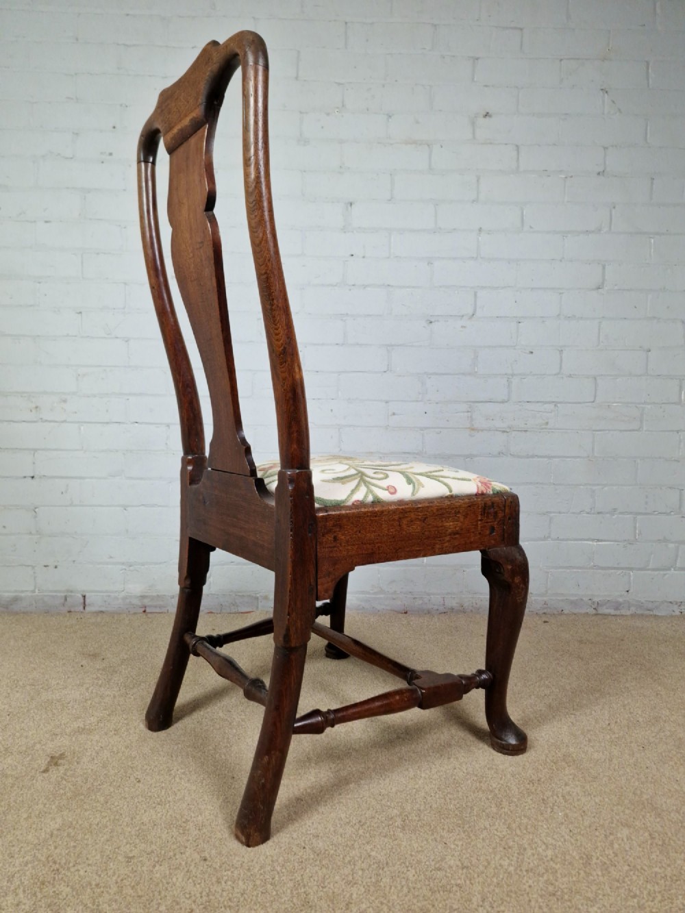 An early 18th century Queen Anne wooden dining chair featuring cabriole front legs, a vasiform back splat, and a patterned drop-in seat cushion. View IV