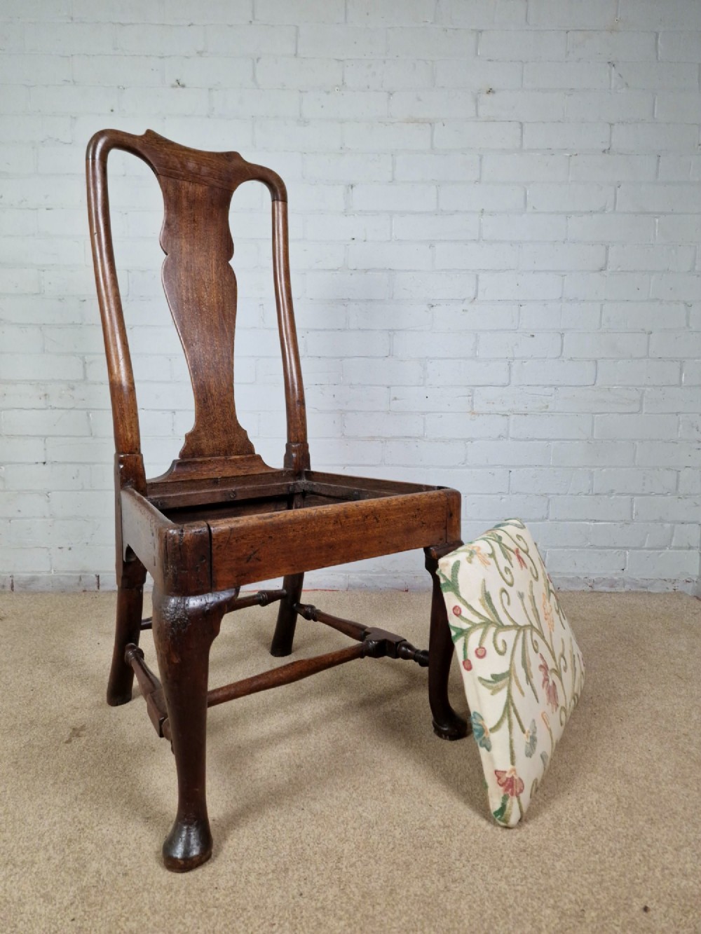 An early 18th century Queen Anne wooden dining chair featuring cabriole front legs, a vasiform back splat, and a patterned drop-in seat cushion. View V