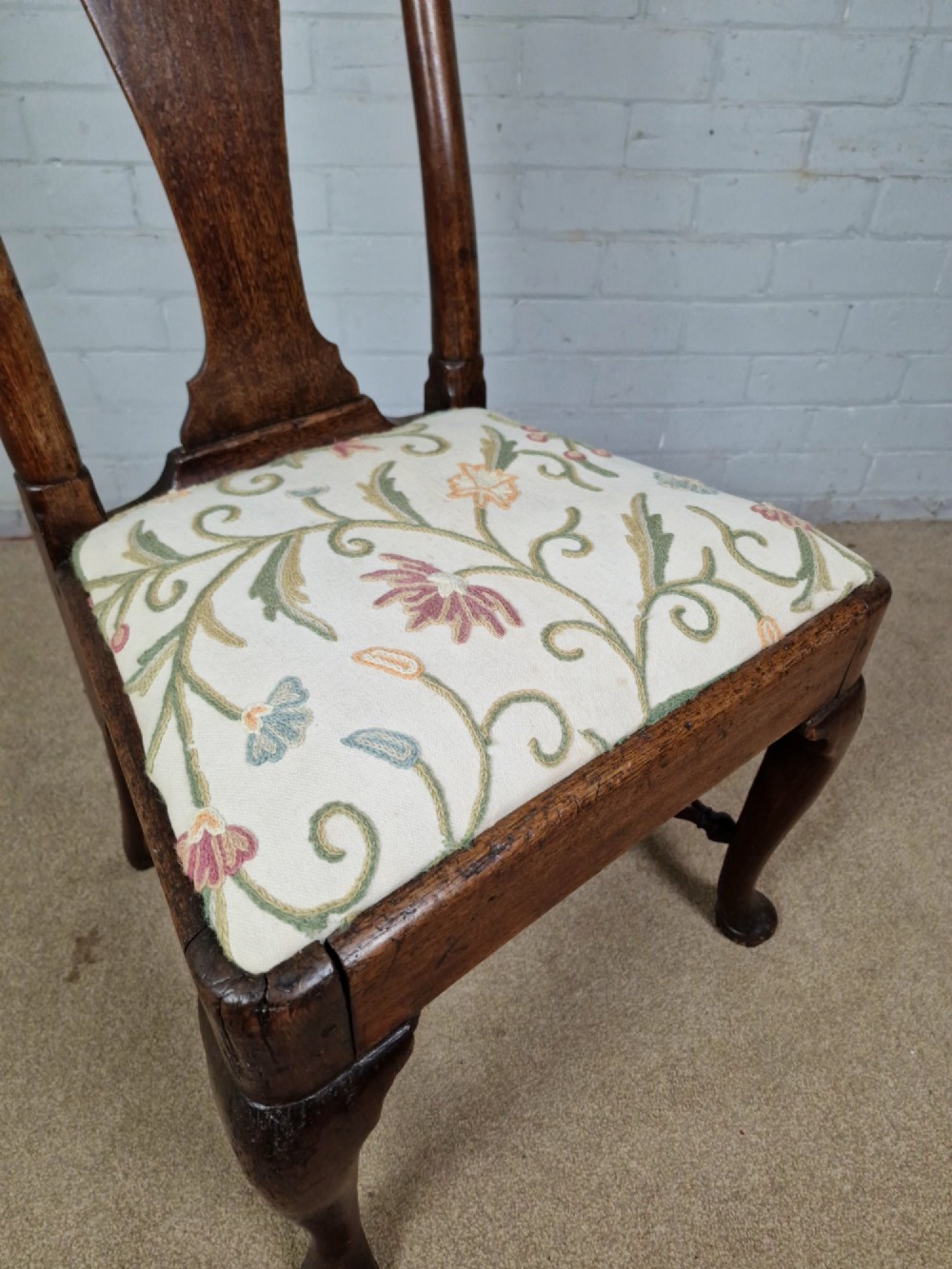 An early 18th century Queen Anne wooden dining chair featuring cabriole front legs, a vasiform back splat, and a patterned drop-in seat cushion. View VII
