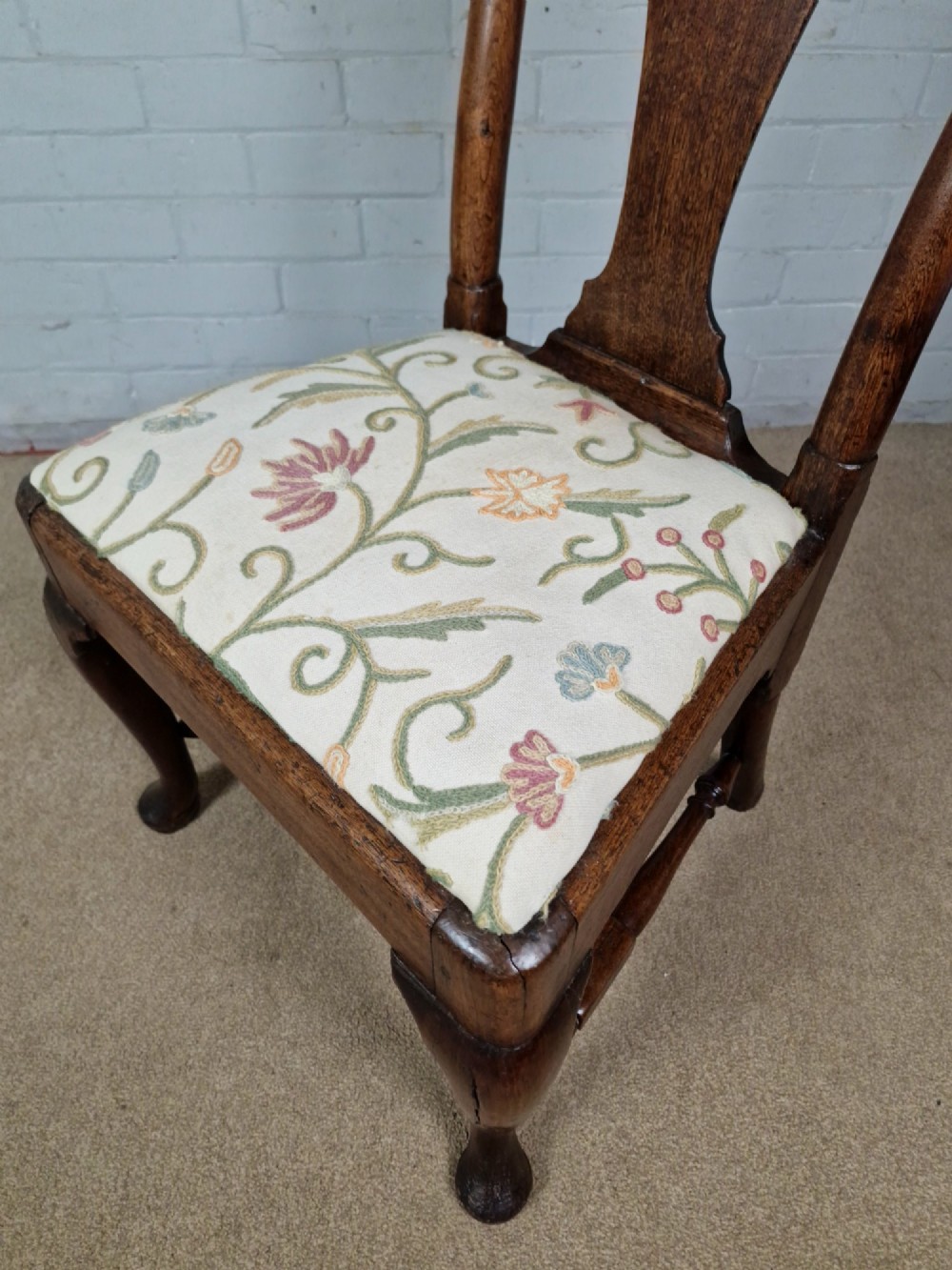 An early 18th century Queen Anne wooden dining chair featuring cabriole front legs, a vasiform back splat, and a patterned drop-in seat cushion. View VIII