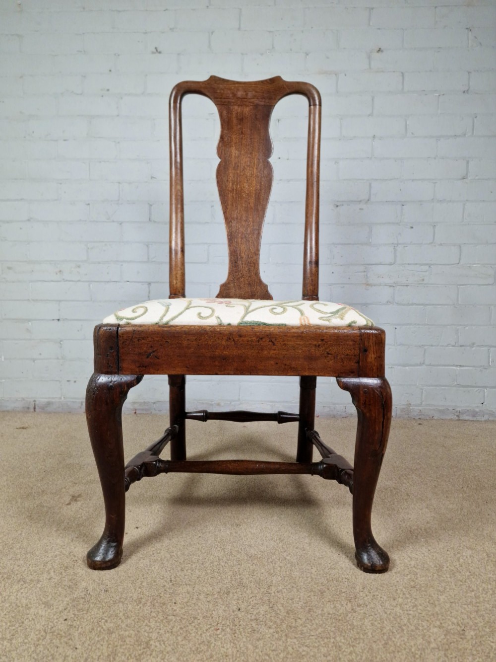 An early 18th century Queen Anne wooden dining chair featuring cabriole front legs, a vasiform back splat, and a patterned drop-in seat cushion. View XI
