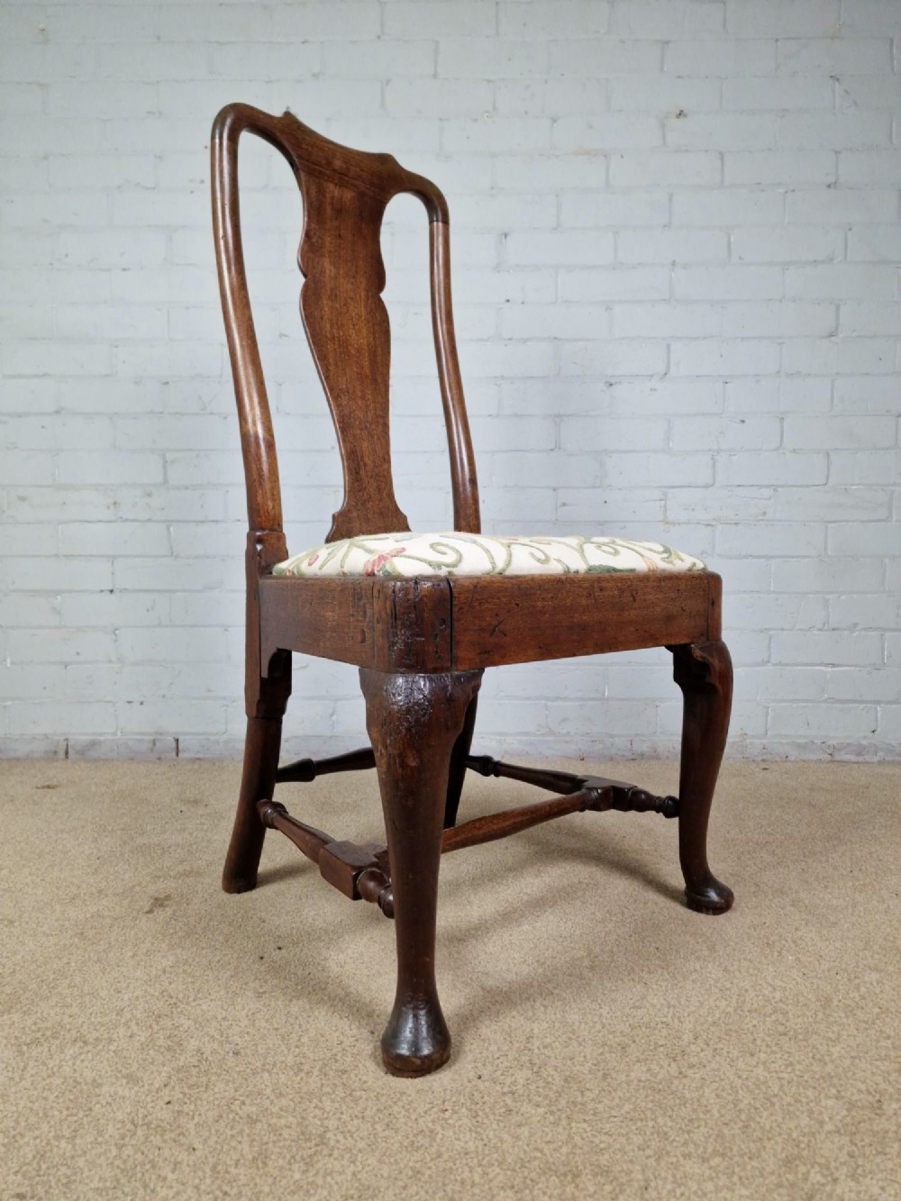 An early 18th century Queen Anne wooden dining chair featuring cabriole front legs, a vasiform back splat, and a patterned drop-in seat cushion. View XII