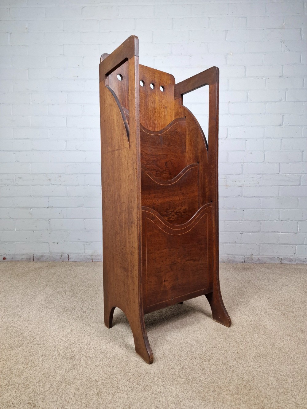 A tall Arts and Crafts brown oak magazine rack featuring three tiered compartments, circular cut-out details at the top, and integrated side carry handles. View IV