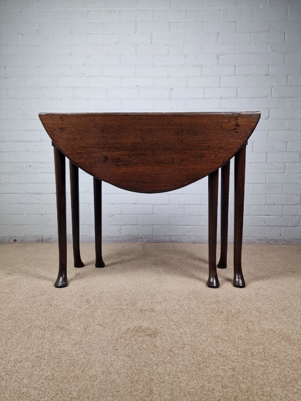 An 18th-century Georgian dark oak gateleg table with hinged leaves and slender tapered legs ending in pad feet. View III
