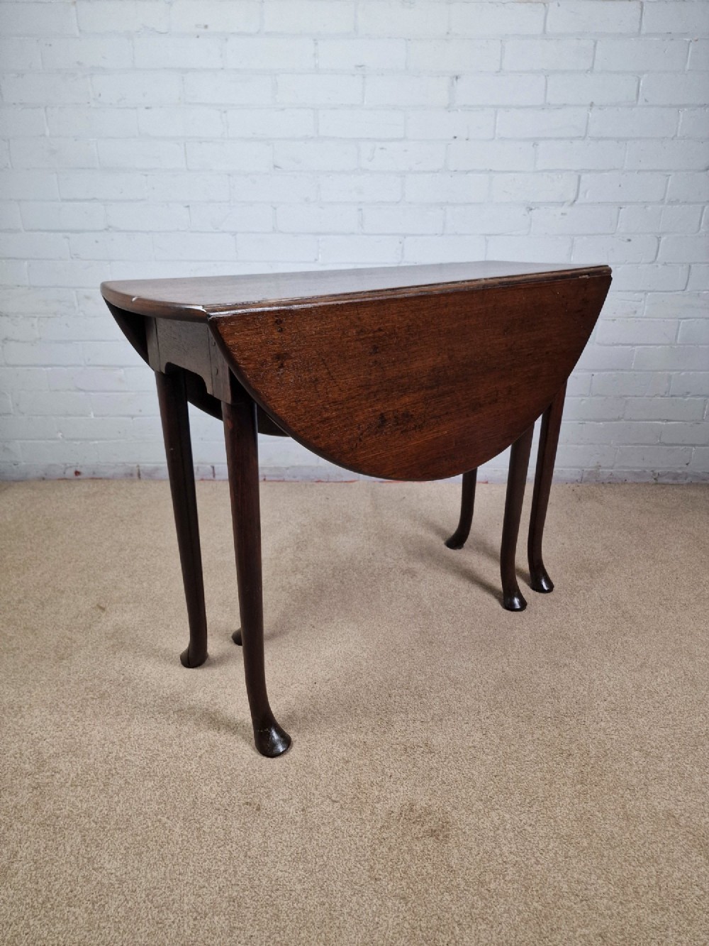 An 18th-century Georgian dark oak gateleg table with hinged leaves and slender tapered legs ending in pad feet. View IV