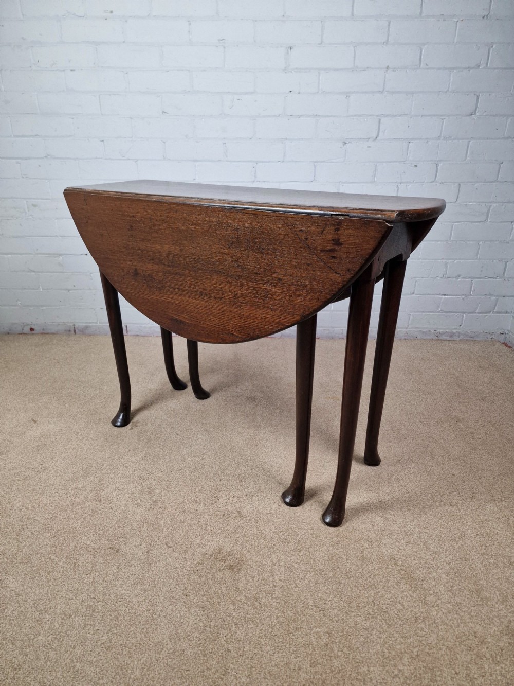 An 18th-century Georgian dark oak gateleg table with hinged leaves and slender tapered legs ending in pad feet. View V