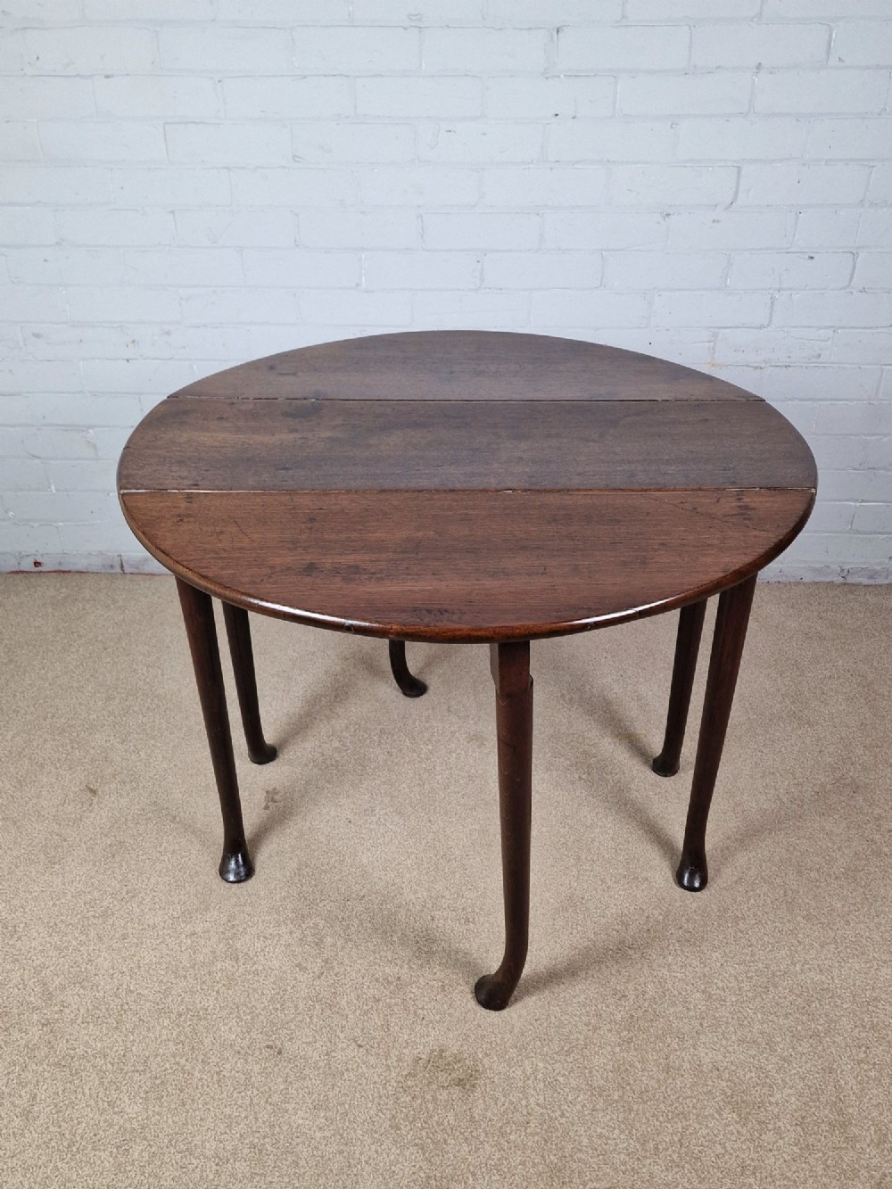 An 18th-century Georgian dark oak gateleg table with hinged leaves and slender tapered legs ending in pad feet.